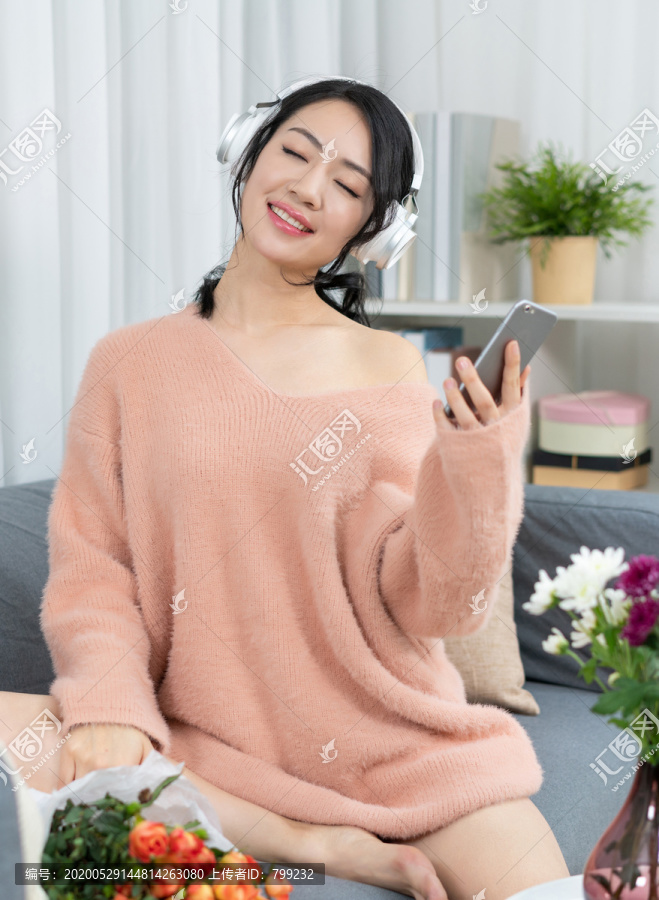 年轻女子坐在沙发上听音乐