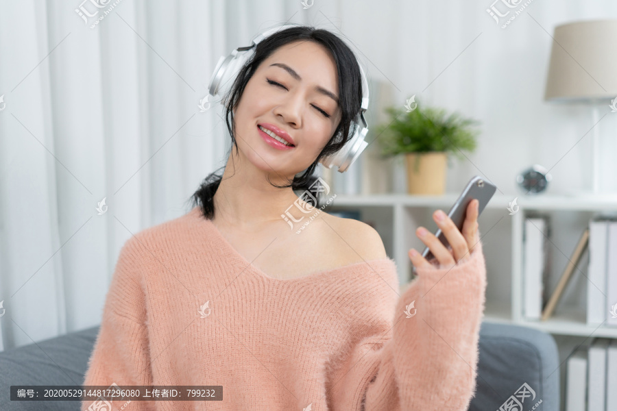 年轻女子坐在沙发上听音乐