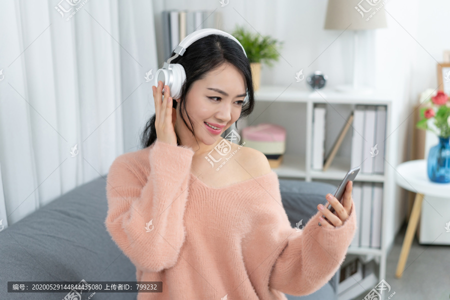 年轻女子坐在沙发上听音乐