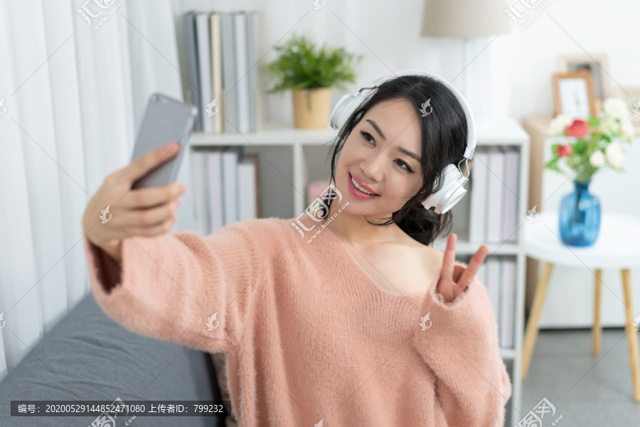 年轻女子坐在沙发上听音乐