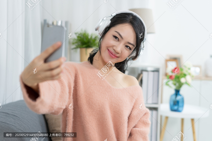 年轻女子坐在沙发上听音乐