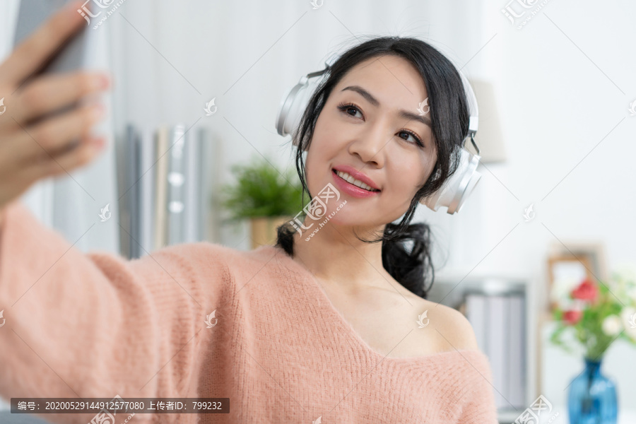 年轻女子坐在沙发上听音乐