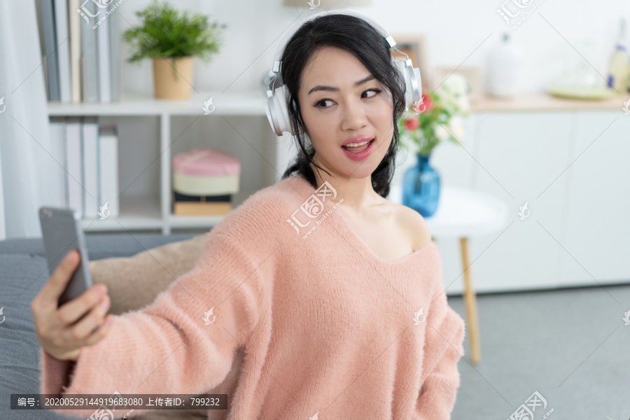年轻女子坐在沙发上听音乐
