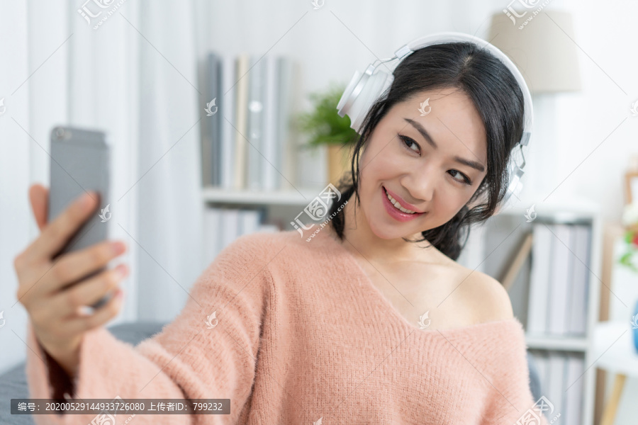 年轻女子坐在沙发上听音乐
