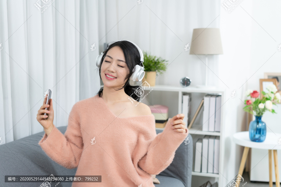 年轻女子坐在沙发上听音乐