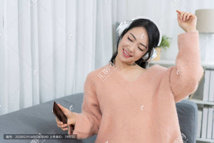年轻女子坐在沙发上听音乐