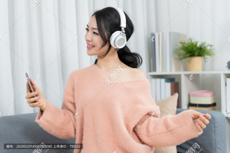年轻女子坐在沙发上听音乐