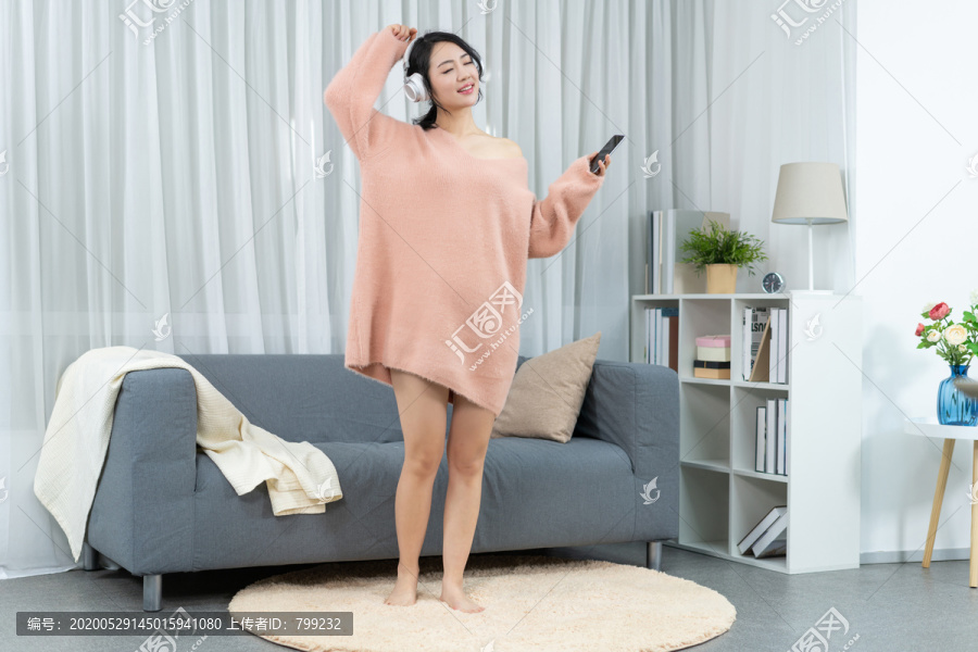 年轻女子坐在沙发上听音乐