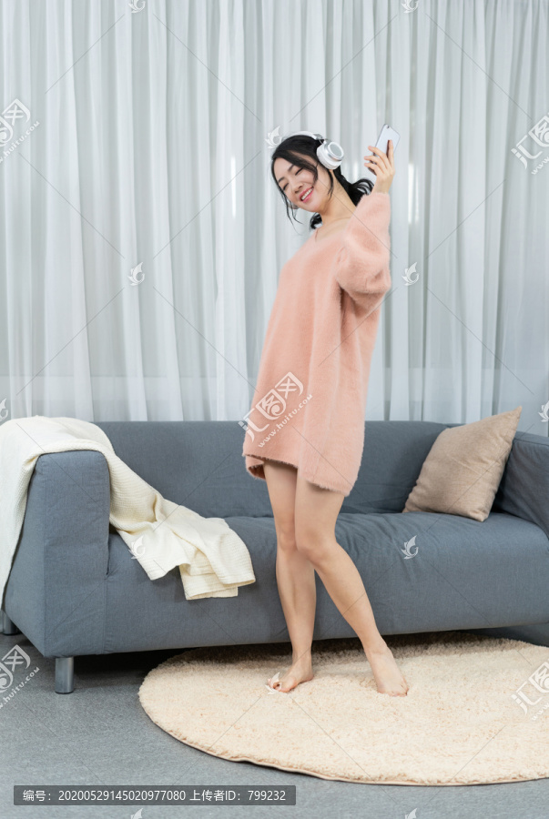 年轻女子坐在沙发上听音乐