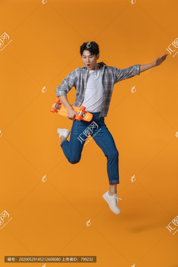 拿着滑板跳跃的年轻男子