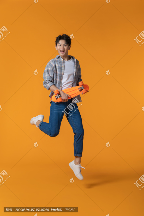 拿着滑板跳跃的年轻男子