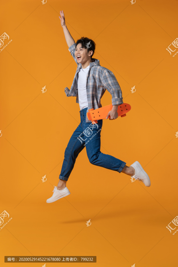 拿着滑板跳跃的年轻男子