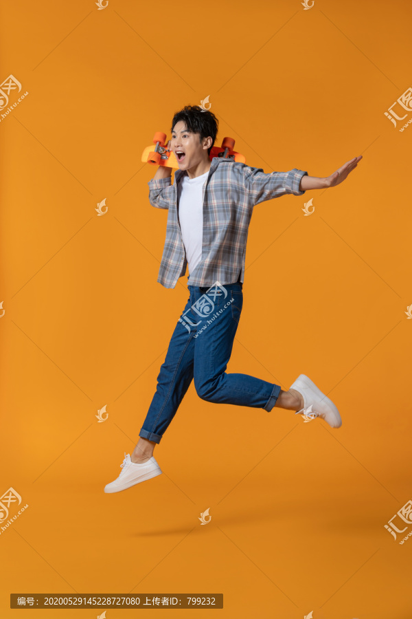 拿着滑板跳跃的年轻男子