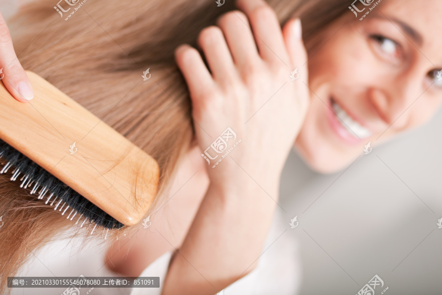 一个穿着睡衣的年轻女人早上起床后梳着她长长的深金色头发