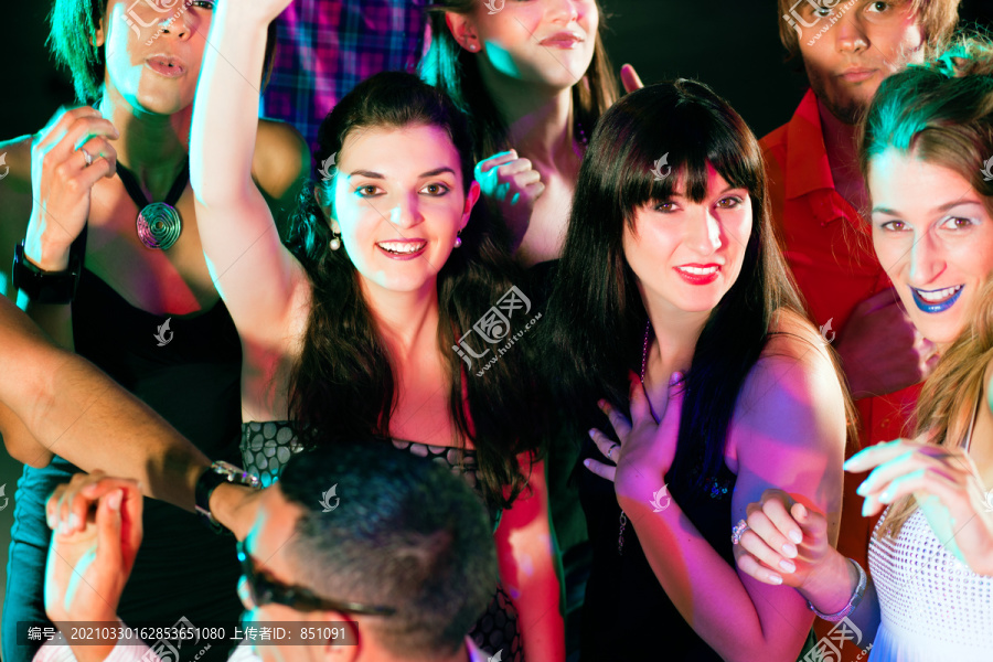 一群不同种族的男女朋友在迪斯科俱乐部里随着音乐跳舞，玩得很开心