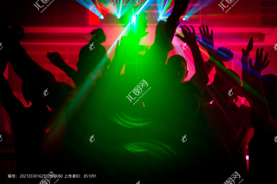 跳舞的人们在迪斯科俱乐部举行庆祝活动的剪影，灯光秀通过背光发射激光束