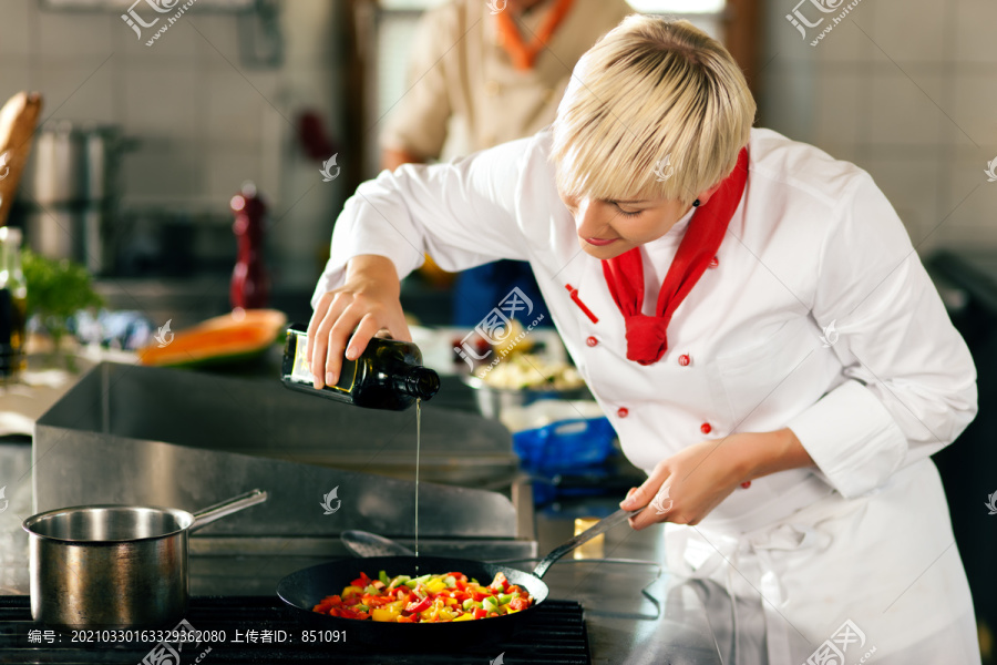 两个厨师团队合作-男人和女人-在餐厅或酒店厨房烹调美味的食物，她是把橄榄油在鼠王