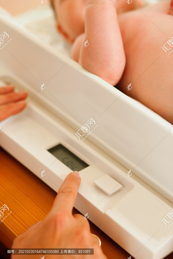 婴儿在体重秤上，母亲或医生正在检查新生儿的健康和发育情况