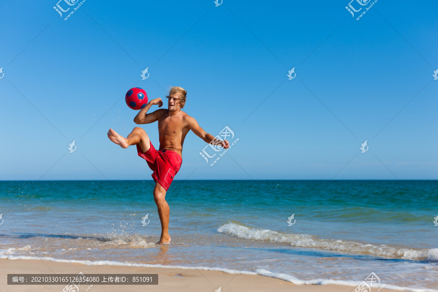 在海滩上踢足球的年轻人