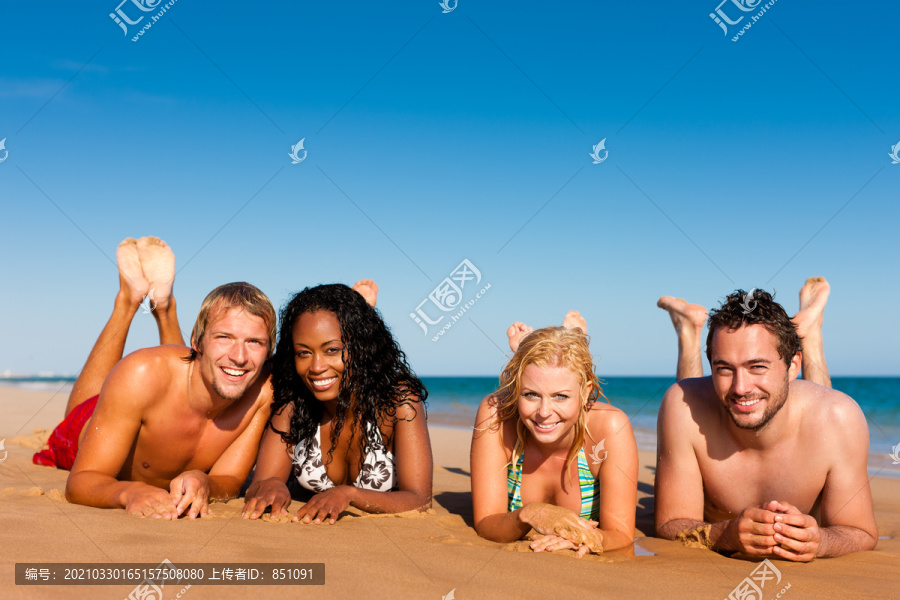 四个朋友组成的小组-男人和女人-在海滩上享受假期的乐趣