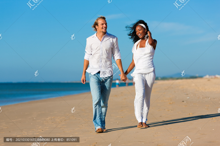 一对幸福的夫妇——黑人女人和白人男人——度假时在海滩上散步和跑步