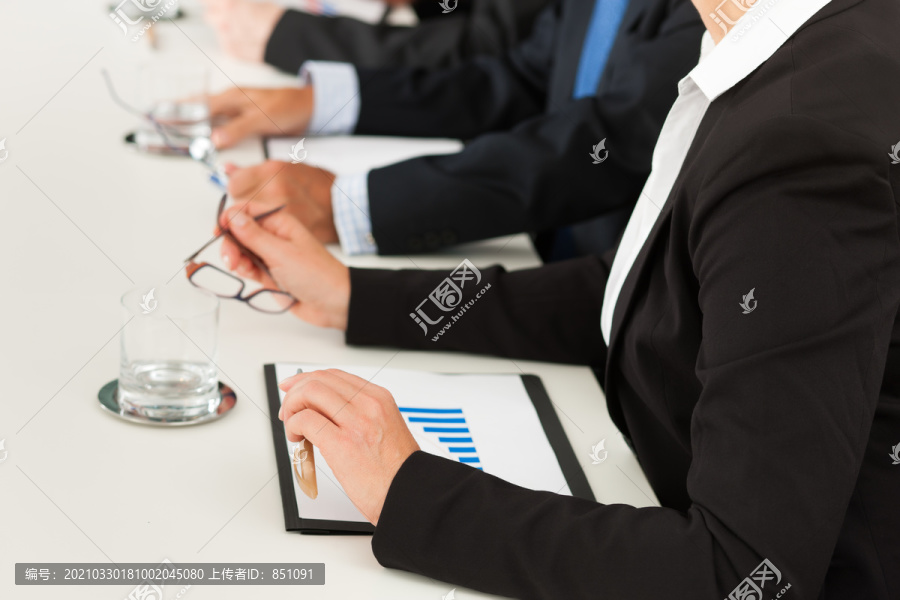商务人士坐在会议上，特写镜头在手上，女人在前面