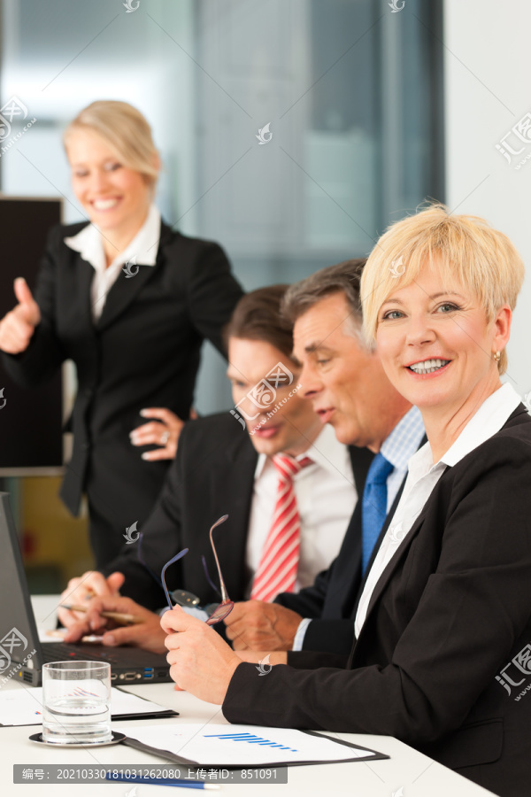 商务团队会议在办公室里用笔记本电脑，老板和他的员工，一个女人正看着摄像机