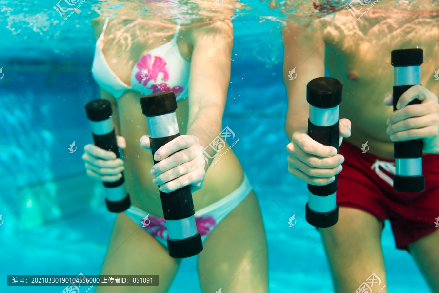 健身-一对年轻夫妇（男男女女）在游泳池或水疗中心的水下用哑铃做运动和体操或水上有氧运动
