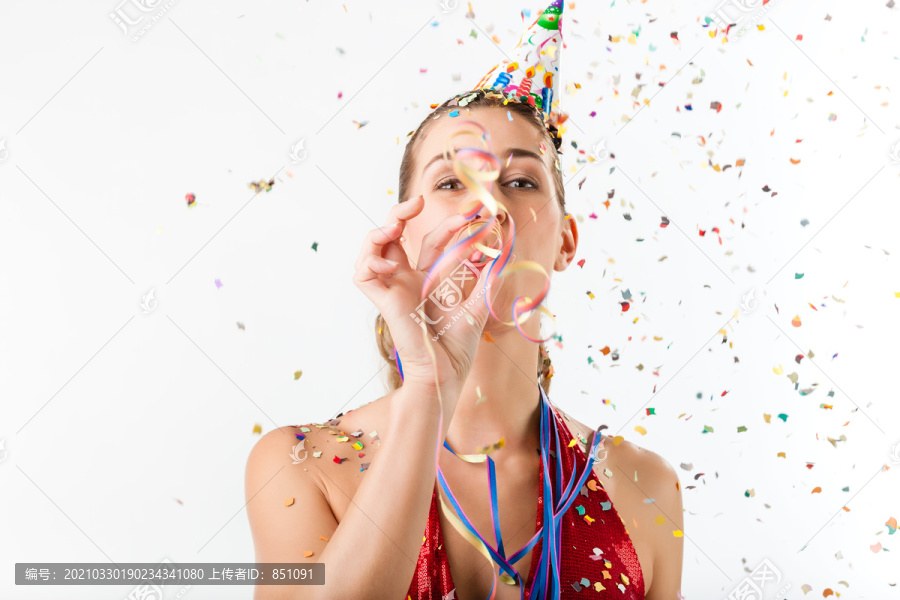 庆祝生日或除夕的女人，在五彩纸屑的簇拥下用喇叭鸣叫