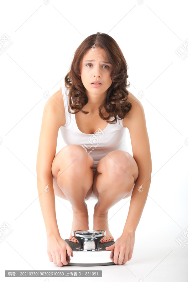 饮食和体重，年轻女子坐在她的臀部的规模