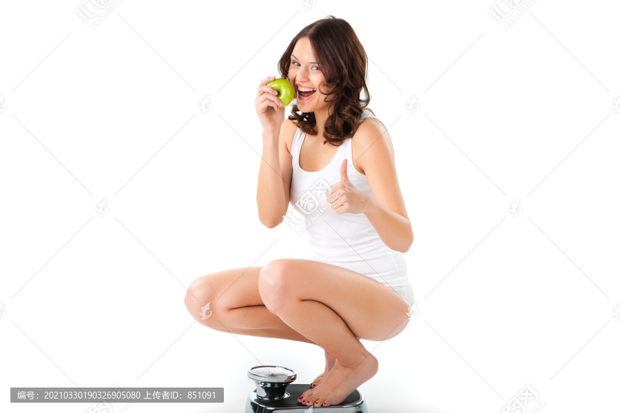 饮食和体重，年轻女子坐在她臀部的天平上，她对成功感到高兴