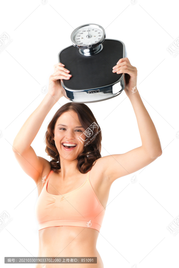 饮食和体重-年轻女子用体重秤，她对成功感到高兴