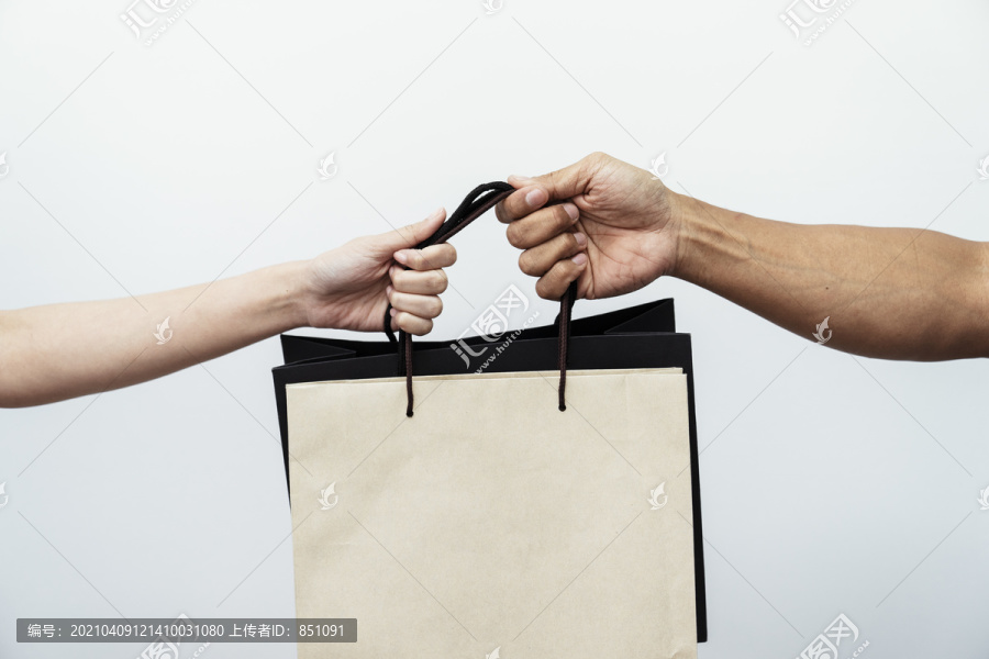 两个人手拿购物纸袋在白色背景上隔离在一起。