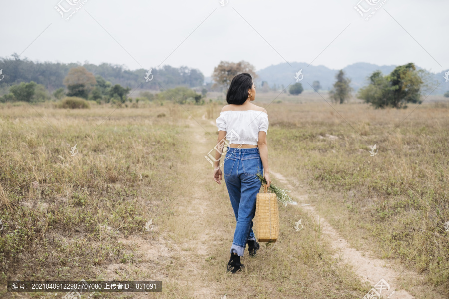 背景——来自首都的孤独女孩提着装满午餐的篮子走向田野。