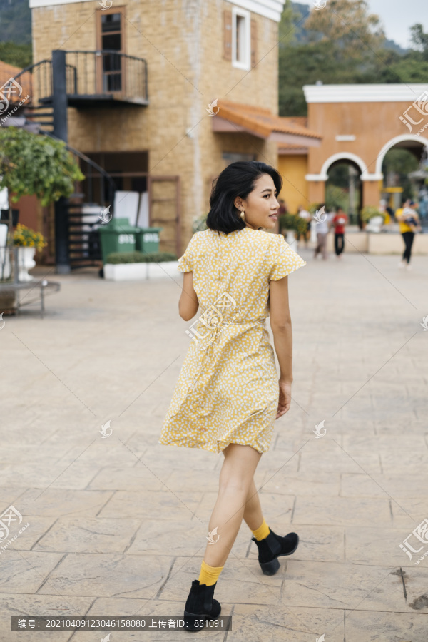 穿着黄色连衣裙的亚洲年轻女子在中世纪小镇旅行。