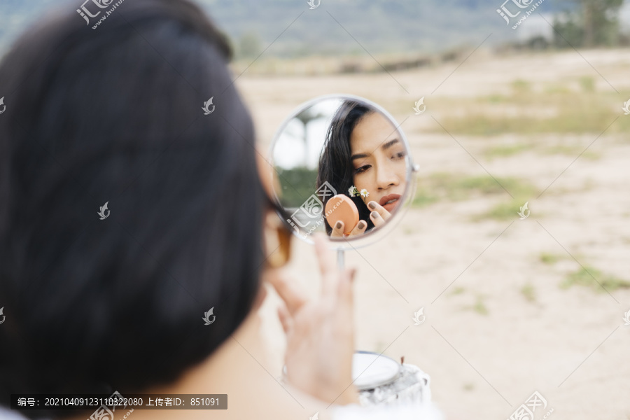 亚洲女人在户外小镜子上化妆的特写镜头。