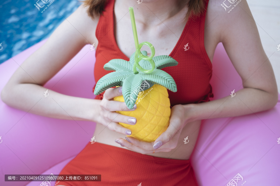 特写镜头美丽性感的泰国女子在红色比基尼举行菠萝塑料瓶。