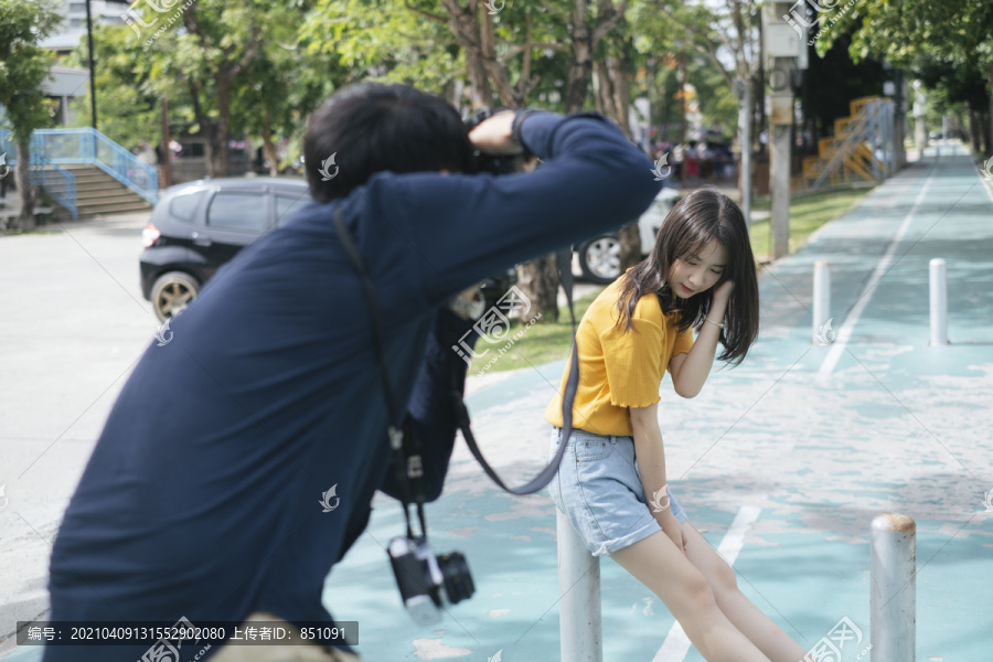 男摄影师和少女模特在自行车道上拍照。