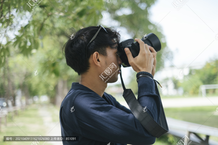 男摄影师拍摄树叶、树木和天空的照片。