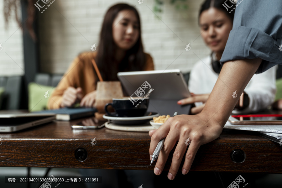 两位年轻女士在平板电脑上一起工作，而她的老板正在观看。日常生活中的现代技术。两位女商人的同事在讨论如