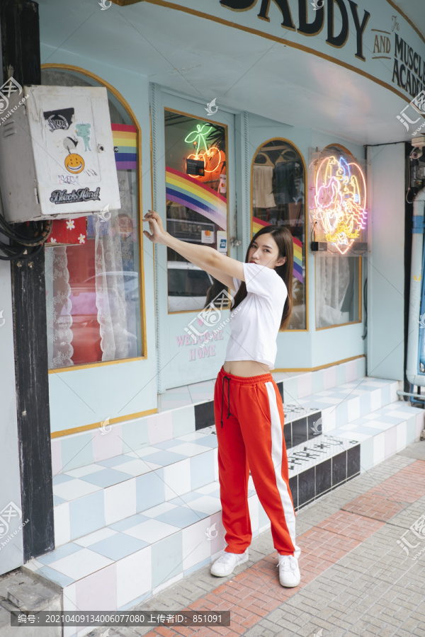 时尚写真-身穿白色衬衫和红色运动裤的泰国亚裔年轻女子伸出手。