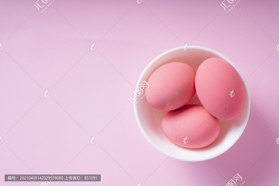 顶视图-三个粉红色的鸡蛋在白色的碗里粉红色的背景。