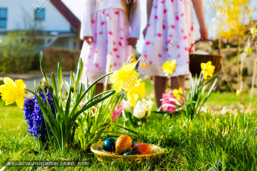 春天，孩子们在草地上寻找复活节彩蛋，前景是一个装满彩蛋的篮子