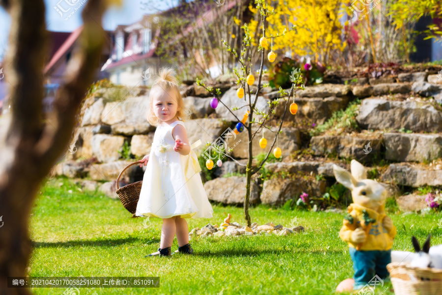 春天，小女孩在草地上寻找复活节彩蛋，她手里拿着一个篮子或复活节篮子