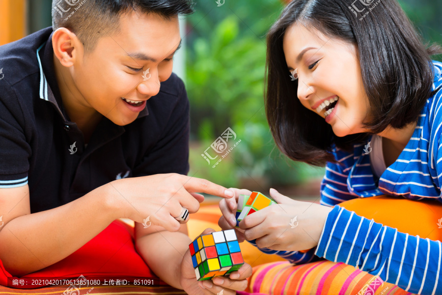 年轻的印尼夫妇-男人和女人-在家玩魔方