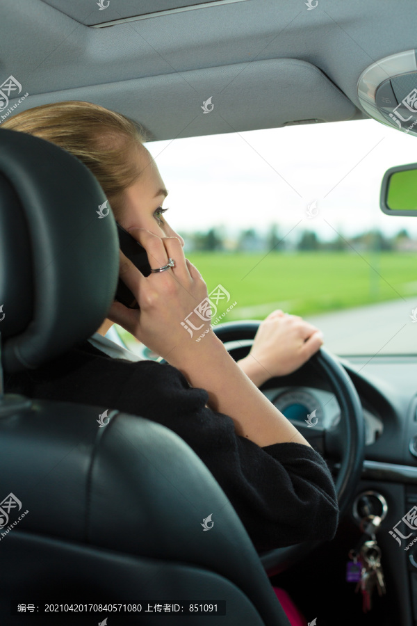 带电话的年轻女子一边开车一边打电话