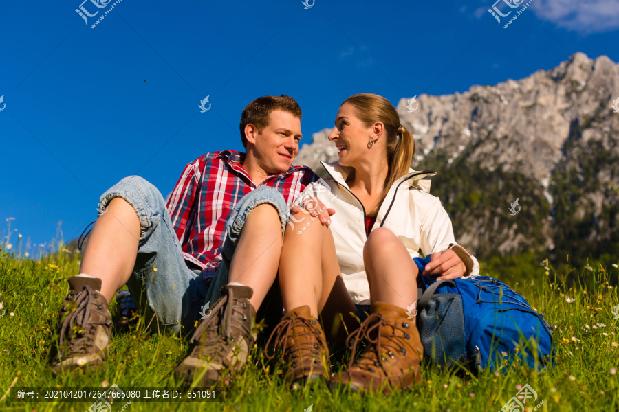 一对幸福的情侣在阿尔卑斯山的草地上散步，休息一下，欣赏山景