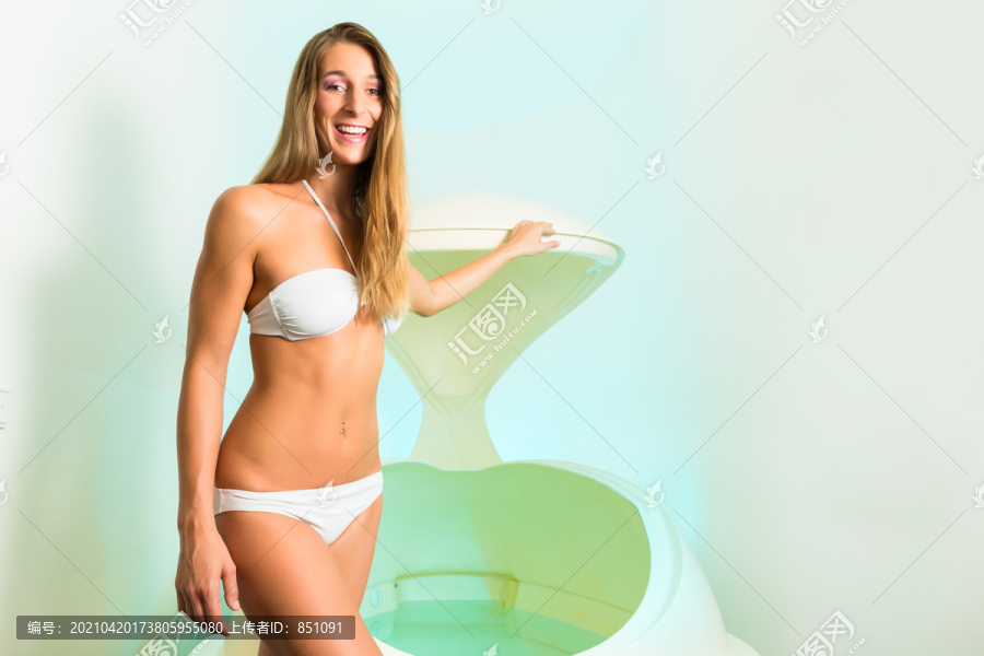 健康-年轻女子漂浮在水疗中心或游泳池，旁边的浮动浴缸