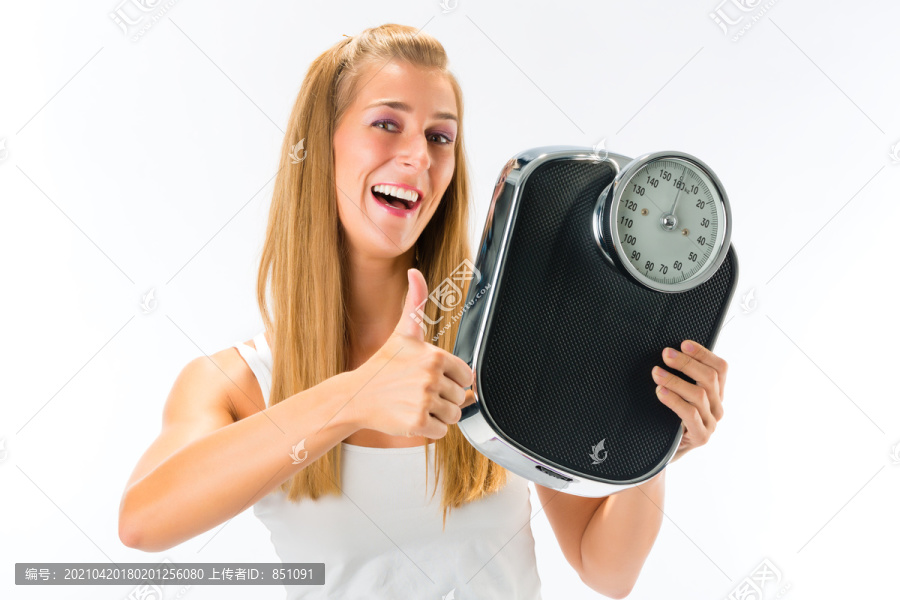 饮食和体重，有体重秤的年轻女子，她对自己的成功感到高兴