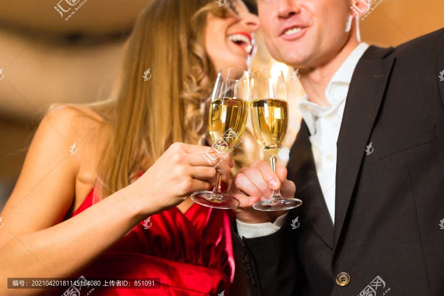 一对男女，在一家高级餐厅里喝香槟，每人手里都拿着一杯起泡酒